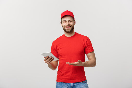 Smiling Delivery Man With Tablet In Studio. Isolated Gray Background