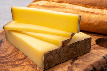 French food -  piece of cheese comte made from cow milk in region Franche-Comte in France and fresh baked baguette bread.