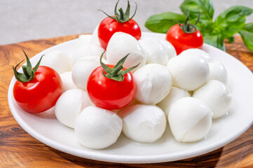 Italian tricolore, small balls of fresh white soft Italian mozzarella cheese, ripe red cherry tomatoes and fresh green basil herb, ready for making caprese salad