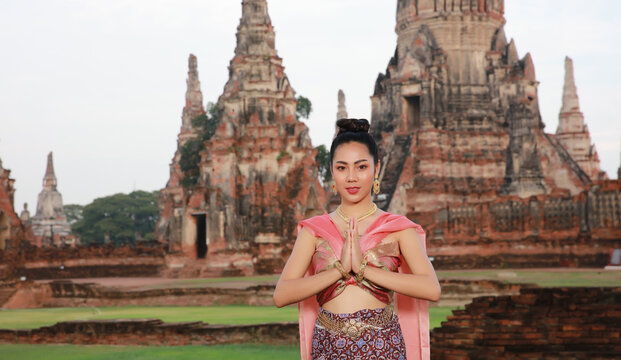 Portrait Thai woman dress traditonal uniform hand up pray respect or welcom greeting  lifestyle at Wat Chai Wattanaram, Ayuttaya,Thailand