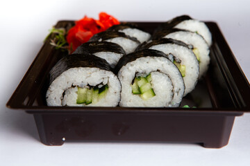 Japanese food rolls in plastic box. Sushi set in a plastic package close up isolated on a white background. Sushi for take away or sushi delivery.