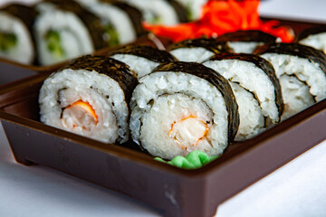 Japanese food rolls in plastic box. Sushi set in a plastic package close up isolated on a white background. Sushi for take away or sushi delivery.