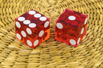 Two red glass dice on a wicker round rug. The result is 