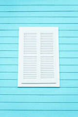 White Louvered Window Shutter on a Light Blue Wooden Building