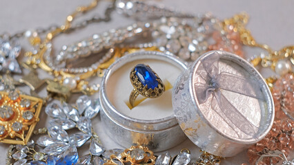 Antique ring with blue gemstone in box and jewel set. Beautiful fashion and vintage jewelry with precious shiny stones, pearls and diamonds for women. Background of Many yellow white gold and silver 