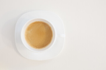 Close up top view of a white porcelain cup of coffee on soucer isolated on white background with copy space on left side