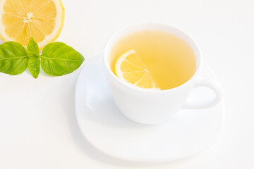 Cup of green tea with lemon slice, basil and mint isolated on white background