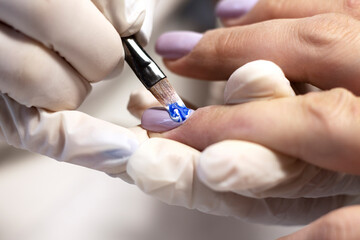 Nail design. The process of coating the nails with gel polish and drawing the design with a brush by a specialist in a beauty salon. Close-up. Space for text