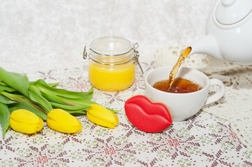 Side view of the pouring of tea, flowers, cookies and honey. Selective focus