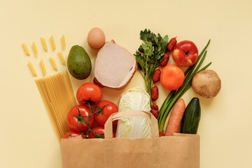Grocery, food products stuff in the paper bag on the light yellow background.