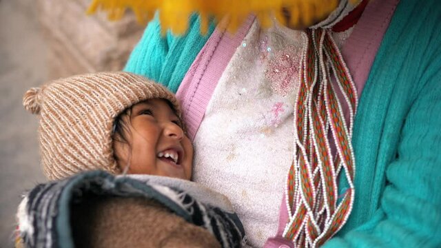 Heartwarming moment at Plaza de Armas, Cusco, Peru: a child smiles on their mother's chest. The historic square adds cultural richness to this tender scene, highlighting the warmth of South America.