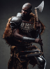 African guy dressed in military nordic costume holding an axe