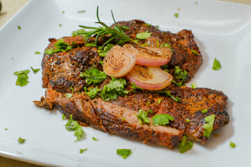 Marinated steak sliced in pieces with cilantro in a cutting board