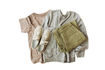 women's clothing in brown, gray, green colors, beige sneakers are beautifully folded on a white background, top view