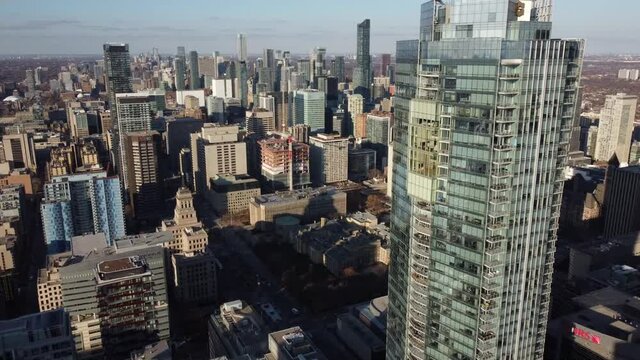 Aerial flying very close to a skyscraper in downtown Toronto and overlooking the skyline and Nathan Phillips Square