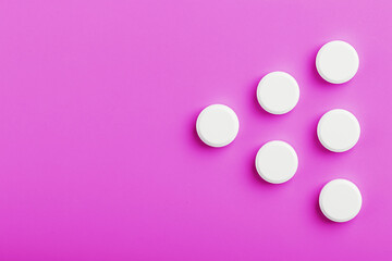 White Ecstasy pills in a row on a pink background, isolate.