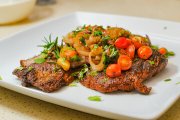 Sliced grilled beef barbecue carne asada steak with cilantro on cutting board on a gourmet dish plate