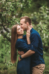 Fototapeta premium Handsome young guy with a girl stand in the spring garden. Romantic couple are walking in the park. Happy relationship concept