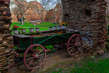 Fototapeta na wymiar Picture of an old wooden cart with flowers, posted between brick walls. Old cart with flowers and pots