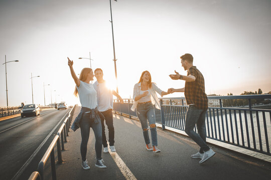 Group of friends hangout at the city street.They walking over the bridge and joying in sunset.	
