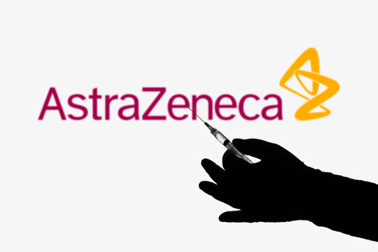 April 8, 2021, Brazil. In this photo illustration the medical syringe is seen with AstraZeneca company logo displayed on a screen in the background.