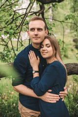 Handsome young guy with a girl stand in the spring garden. Romantic couple are walking in the park. Happy relationship concept