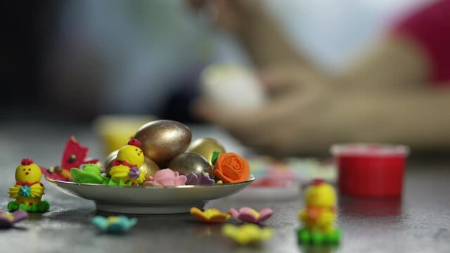 Beautiful composition with Easter eggs. Women's hands paint the egg in different colors and sweets are on the table.