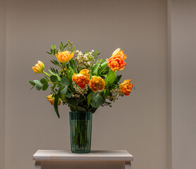 A bouquet of peach and orange colored roses on a small table..