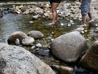 Two people with shorts crossing the rocky river