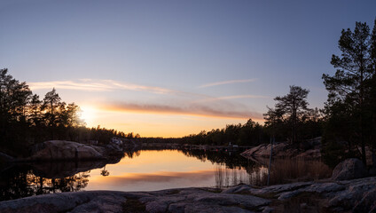 Fototapeta na wymiar Panorama view of sunset in the Swedish archipelago. Rocks, calm water and coastal features this tranquil evening. Photo taken outside Oskarshamn, Sweden