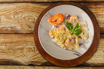 Pasta with shrimps in a creamy sauce on a gray plate on a wooden table