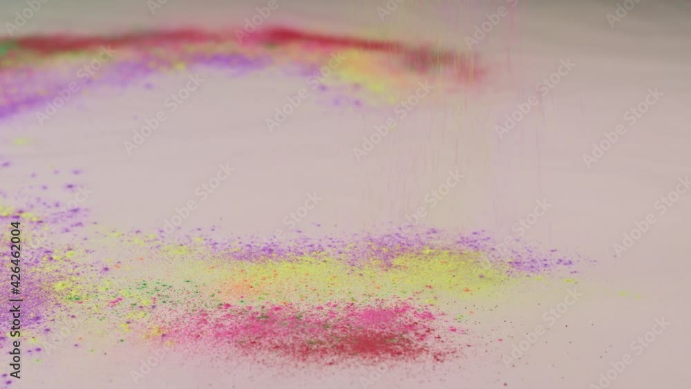 Poster sprinkle several colors of dust on the white paper that is spinning around until the dust is circula