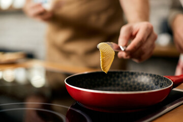 Close-up of man adding butter in frying pan while cooking in kitchen.