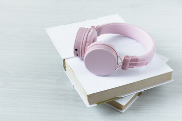 Book and headphones on white wooden table. Audiobook concept.