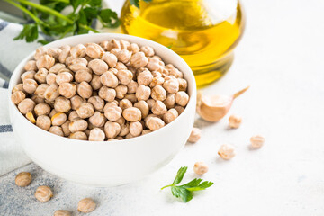 Chickpeas in white bowl at light kitchen table.
