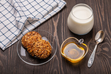 glass of milk, oatmeal cookies and honey on a dark wooden table