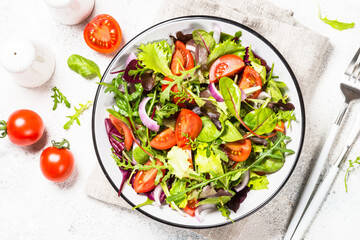 Green salad with fresh vegetables at white.