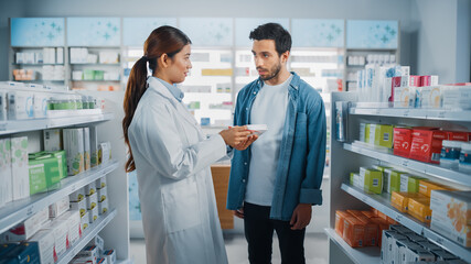 Fototapeta na wymiar Pharmacy Drugstore: Latin Man Chooses to Buy Medicine, Supplements Professional Asian Pharmacist Advicing, Consulting, Recommending Customer the Best Option. Modern Pharma Store Health Care Products