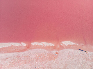 The surface of a pink lake with islands of salt. Top-down view.
