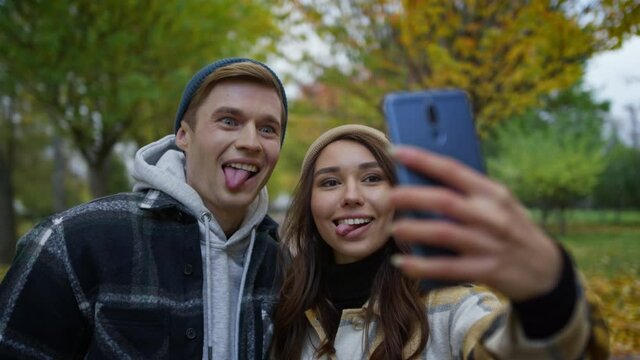 Portrait of beautiful young couple in love taking selfie with tongues.