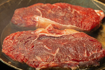 two beef steaks in an iron pan