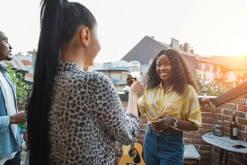 Multi ethnic group of friends hanging out together on rooftop. Happy young people in casual wear...