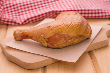 Smoked chicken quarter leg on a wooden board close-up. Smoked, grilled chicken leg close-up.