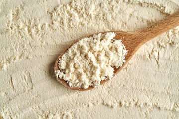Whey protein powder on a wooden spoon, top view