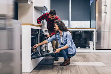 Happy young couple buying household appliances in store.