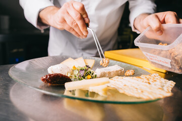 Obraz na płótnie Canvas Chef decorates a cheese plate with tweezers