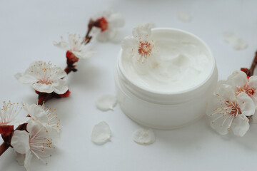 Fototapeta na wymiar face cream and flowers on white background. Beauty industry and healthcare