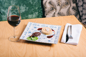 Duck foie gras with sauce on a wooden table and a glass of wine © bodiaphoto