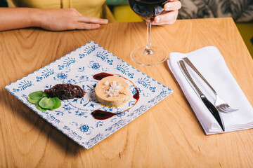 Duck foie gras dish with sauce on a wooden table and a girl with a glass of wine © bodiaphoto
