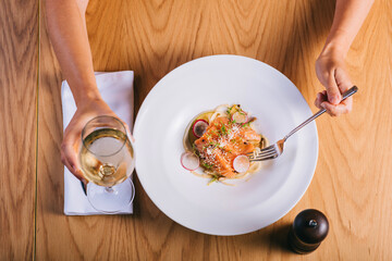 Spaghetti with salmon girl eating with a glass of white wine. Top view